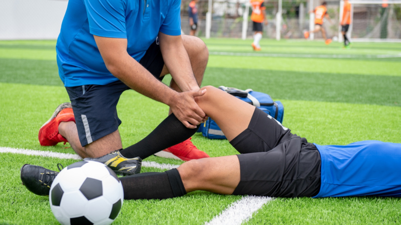 Footballer wearing a blue shirt, black pants injured in the lawn during the race.